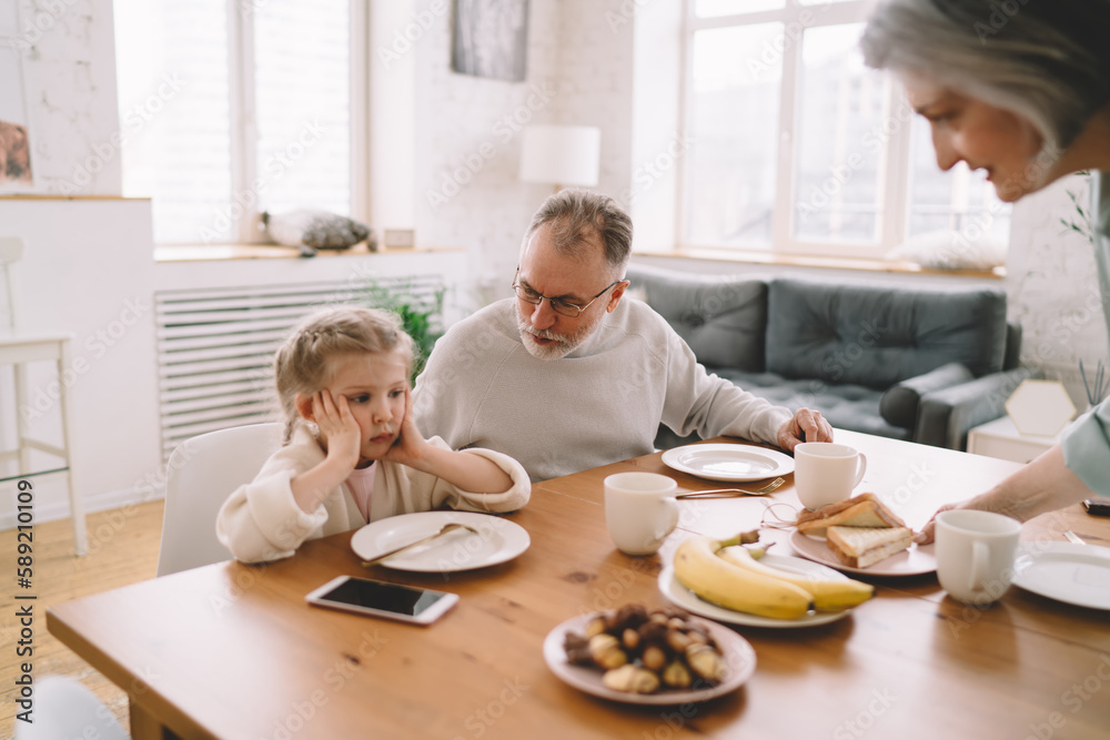 Senior couple having breakfast with little girl Senior couple having breakfast with little girl