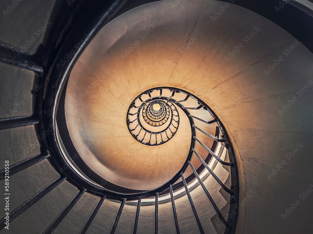 Obraz premium Abstract view of a circular staircase with black metal railing, inside the triumphal arch, Paris, France. Abstract background, a look up underneath an infinite swirl stairs