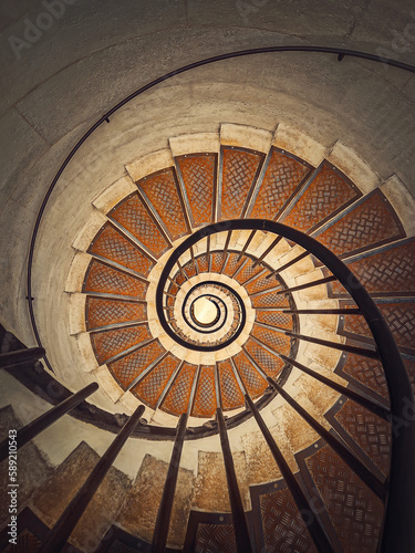 Circular staircase with black metal railing, inside the triumphal arch, Paris, France. Abstract background, a look downstairs an infinite swirl stairway