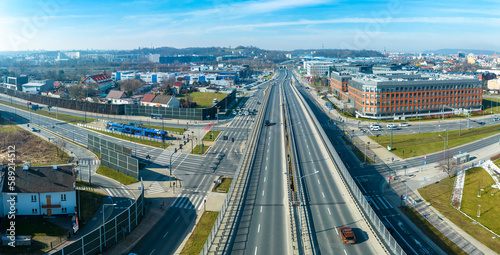 City highway multilevel juntion in Krakow, Poland. Tramway and tram on a tram stop, cars, pedestrian zebra crossings, Aerial panorama. Far view of railway viaducts, train and Krakus Mound