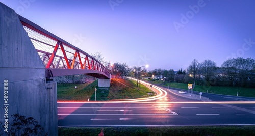 Long exposure of the lights of the cars on the road with a pedestrian bridge at sunset