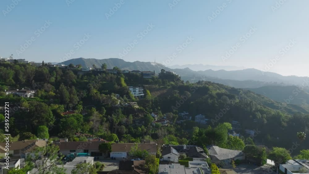 Large luxury real estate houses on Hollywood Hills in Los Angeles on sunny morning. Aerial of Los Feliz area on sunny spring day with Hollywood sign seen in distance on green hills under blue sky 4K Large luxury real estate houses on Hollywood Hills in Los Angeles on sunny morning. Aerial of Los Feliz area on sunny spring day with Hollywood sign seen in distance on green hills under blue sky 4K