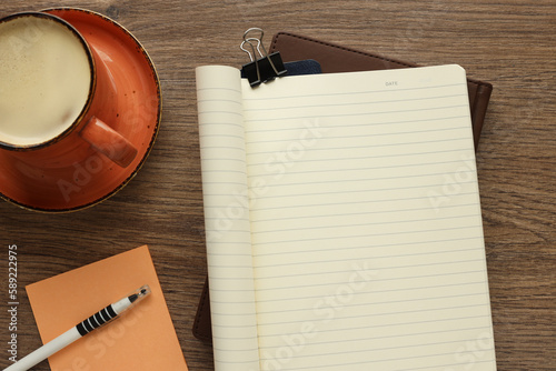 open notepad, coffee cup, white pen, wooden background, spiral notepad on table Business, planning, education, morning life, work from home, concept Top view Flat mockup