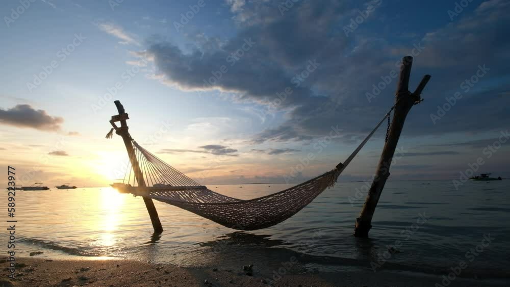Wide angle video shot of a hammock net installed on the shallow sandy beach on Le Morne peninsula, Mauritius. Calm sunset time 4k footage.