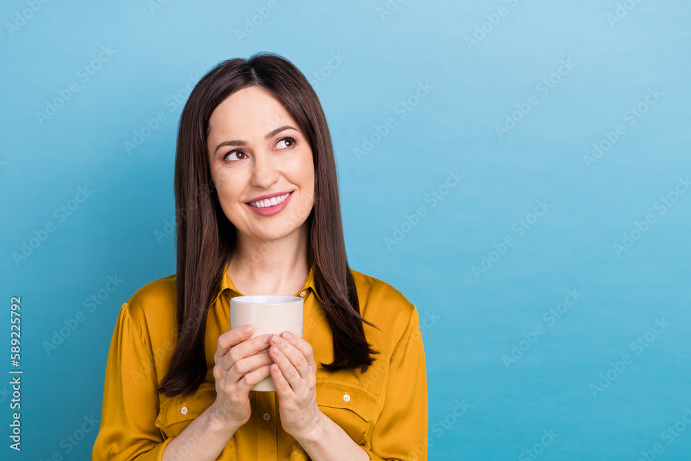 Photo of dreamy young businesswoman wear yellow shirt hold cup hot cacao good morning look empty space good news isolated on blue color background Photo of dreamy young businesswoman wear yellow shirt hold cup hot cacao good morning look empty space good news isolated on blue color background