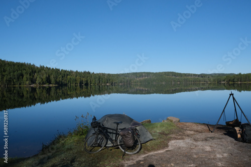 Bicycle and tent on the edge of the calm Øyungen lake in Norway