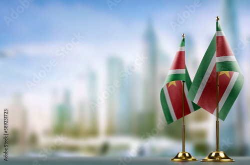Small flags of the Suriname on an abstract blurry background