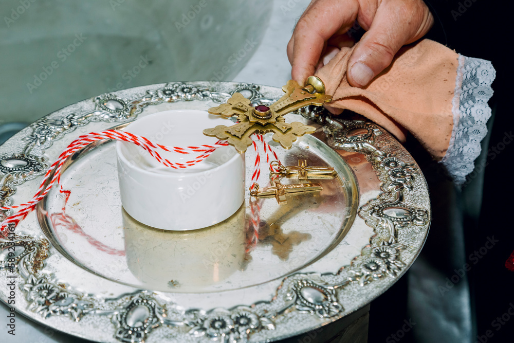 A golden cross in the hand of a priest and two golden crosses on reflective plate in an Apostolic church