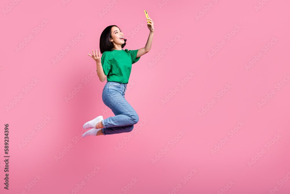 Full length body photo of young active korean girl blogger hold smartphone recording video talking with subscribers isolated on pink color background