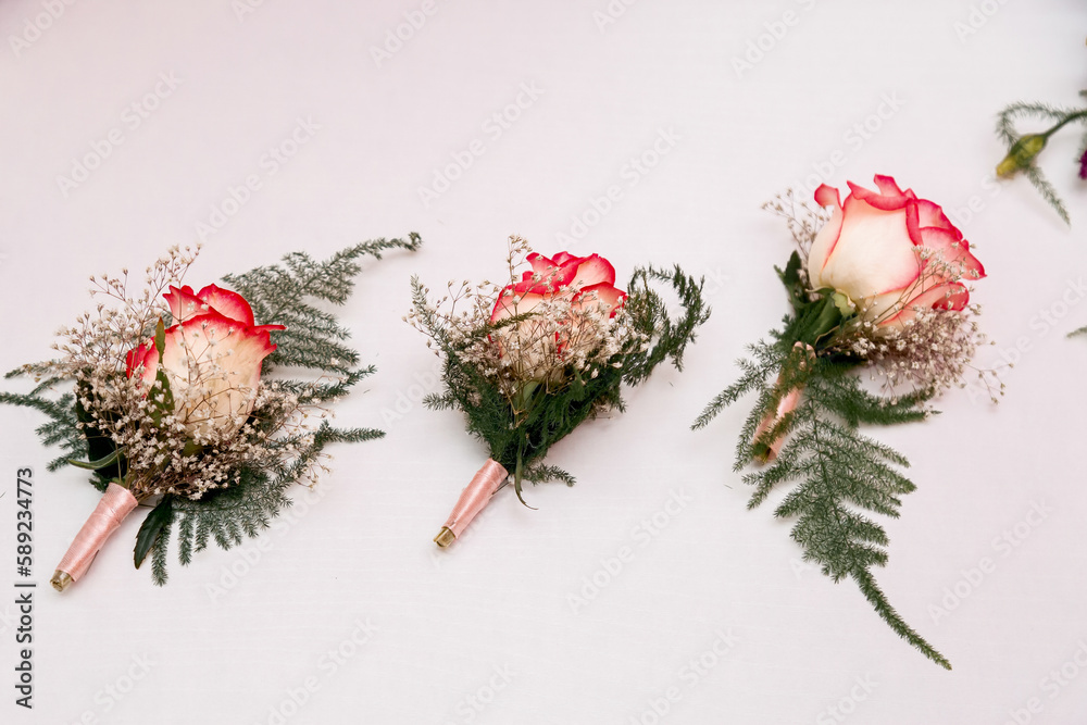 Three tiny roses as wedding ornaments on white background