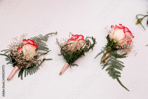 Three tiny roses as wedding ornaments on white background