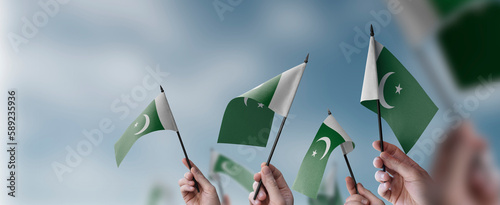 A group of people holding small flags of the Pakistan in their hands