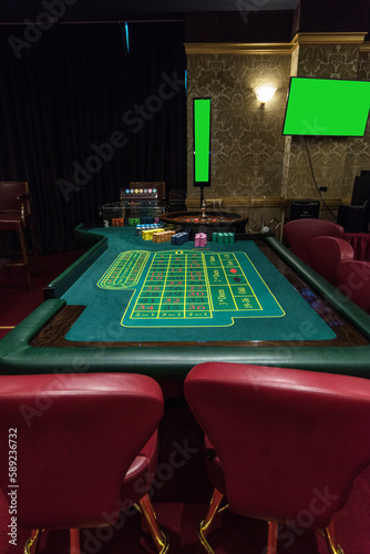 Casino, gambling and entertainment concept - roulette table and stack of poker chips