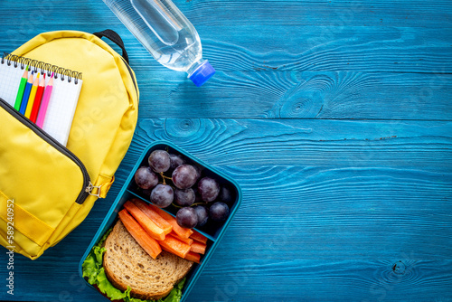 Healthy school lunch box with fruits and backpack, top view