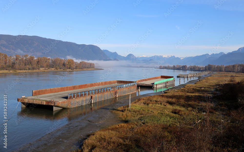 Peaceful river with moored barges and morning fog