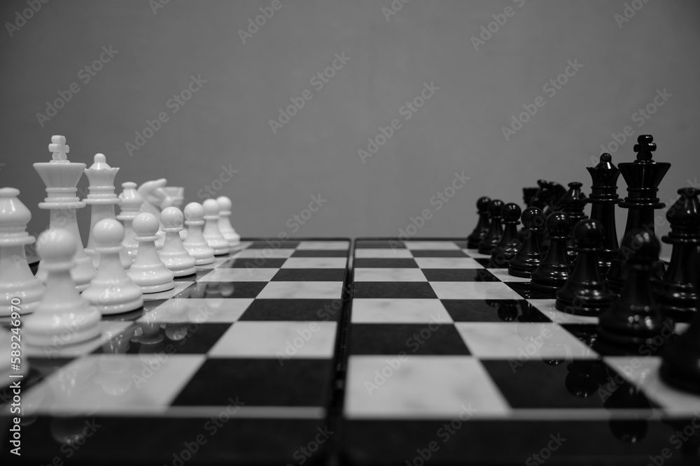 Black and white chess pieces facing each other on chessboard, on gray background. Black and white chess pieces facing each other on chessboard, on gray background.