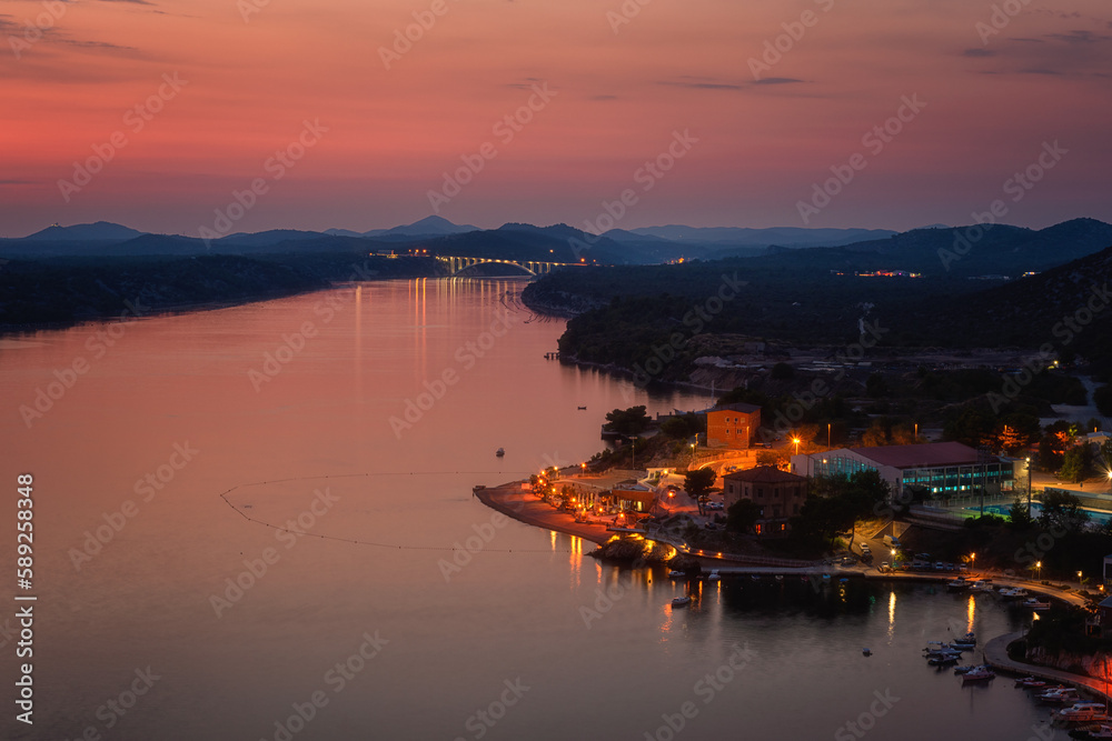 Top view of Sibenik from St Michael’s fortress at twilight, city on Adriatic coast in Dalmatia, Croatia, scenic cityscape with lights, Krka river waterfront and Krka bridge, outdoor travel background