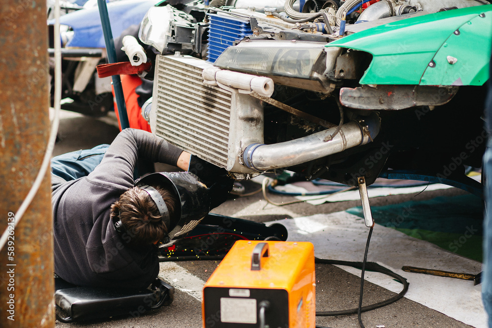 car mechanic quickly repairs a sports powerful car with a large turbocharger on the track car mechanic quickly repairs a sports powerful car with a large turbocharger on the track