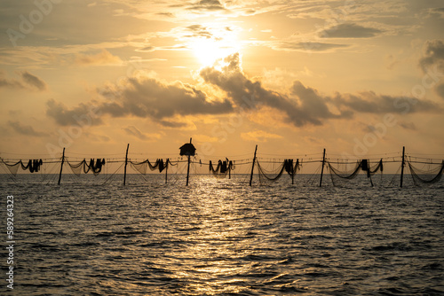 Silhouette of fishermen pulling a nets on fishing poles at sea in Tra Vinh province, Vietnam, Asia during sunrise, local people call it is Day hang khoi. photo