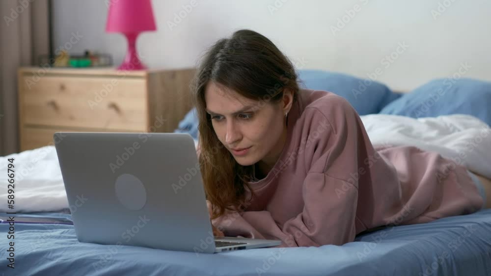 young woman using a laptop computer on bed. High quality 4k footage. young person is looking intently in a laptop young woman using a laptop computer on bed. High quality 4k footage. young person is looking intently in a laptop