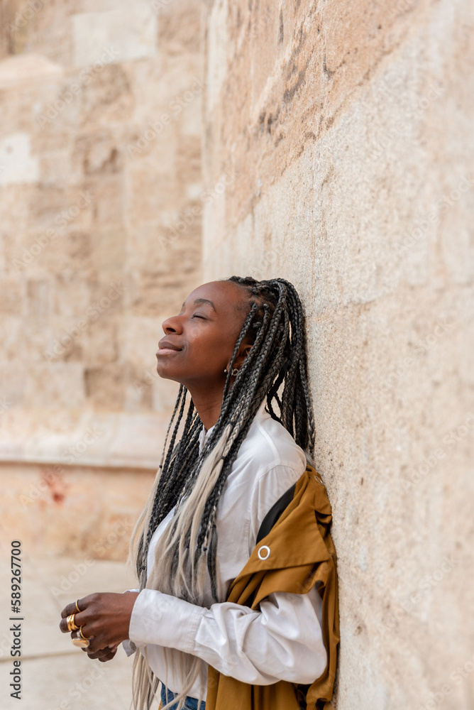 portrait of stylish african american woman with braids with closed eyes leaning against wall portrait of stylish african american woman with braids with closed eyes leaning against wall