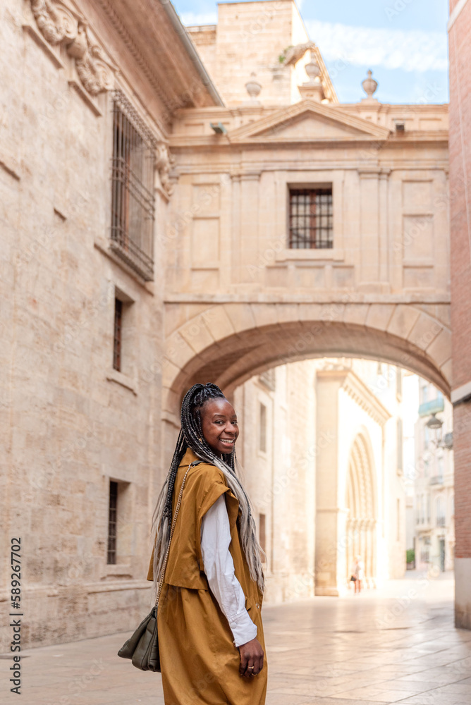smiling African American woman with braids walking through the streets of Valencia in Spain