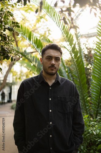 Young man is standing in front of different kind of trees.