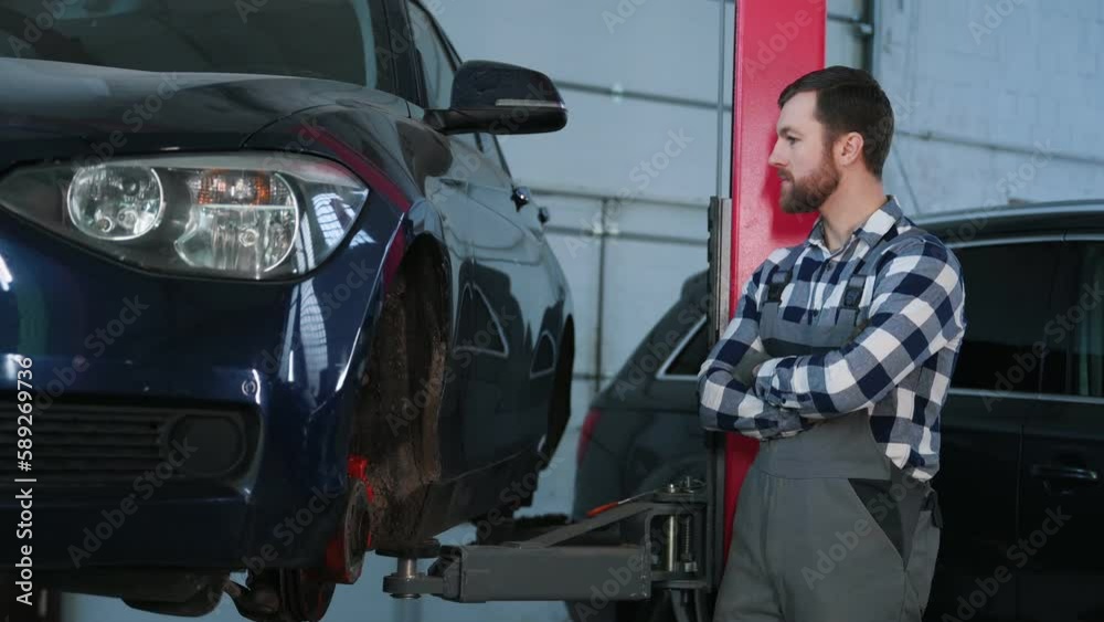 Waiting for the car to uplift. Man is repairing the car at a service station. Waiting for the car to uplift. Man is repairing the car at a service station.