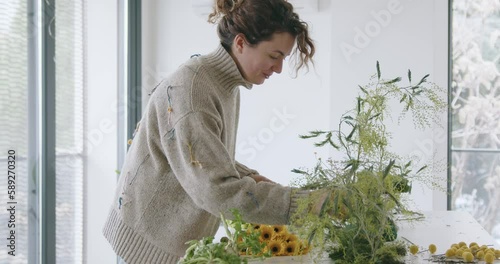 female doing new bouquet. Girl working in flower shop studio. Female florist artist cleans flowers for a beautiful bouquet, workplace view. High quality 4k footage