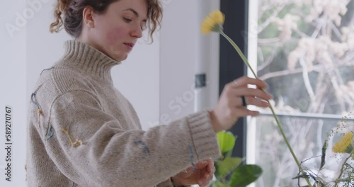 female doing new bouquet. Girl working in flower shop studio. Female florist artist cleans flowers for a beautiful bouquet, workplace view. High quality 4k footage