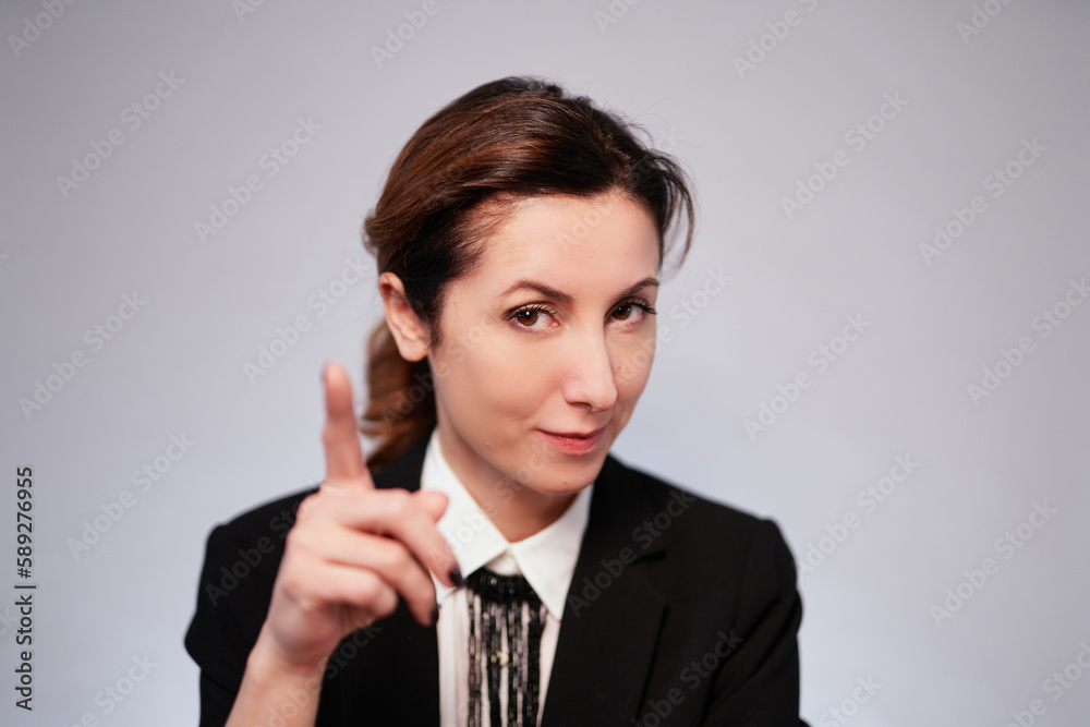 Emotional brunette caucasian business lady in black jacket posing on isolated background pointing at camera with finger. Happy cheerful manager woman in dark suit. High quality photo