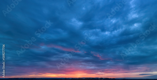 Dramatic sunset, aerial, panoramic photography, minimal horizon. Orange and blue-purple shades of colours, a ray of sunlight penetrating the clouds. Ideal for sky replacement projects. © Martin Mecnarowski