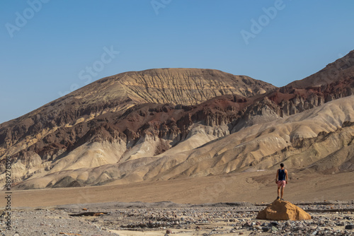 Man with scenic view of colourful multi hued Amargosa Chaos rock formations in Death Valley National Park, Furnace Creek, California, USA. Barren desert landscape of Artist Palette in Black mountains photo