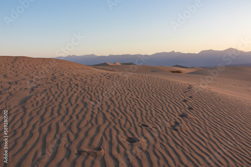 Panoramic view on footprint during sunrise at Mesquite Flat Sand Dunes, Death Valley National Park, California, USA. Morning walk in Mojave desert with Amargosa Mountain Range in back. Natural pattern