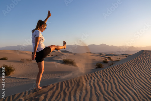 Woman having fun in the sand at sunrise with scenic view on Mesquite Flat Sand Dunes, Death Valley National Park, California, USA. Morning walk in Mojave desert with Amargosa Mountain Range in back photo
