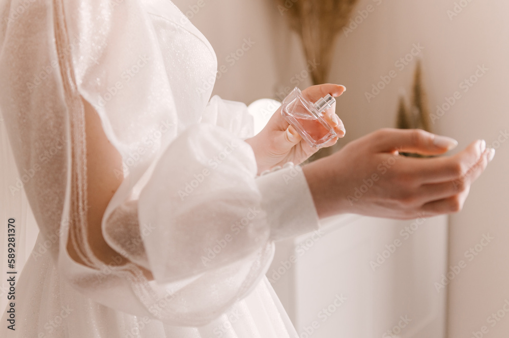 Beautiful young bride with bottle of perfume at home