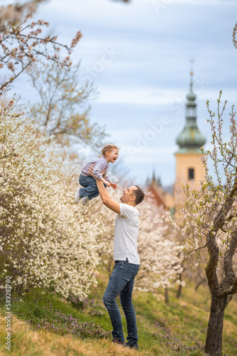 Father and daughter having a fun together under a blooming tree in spring park Petrin in Prague, Europe © dtatiana