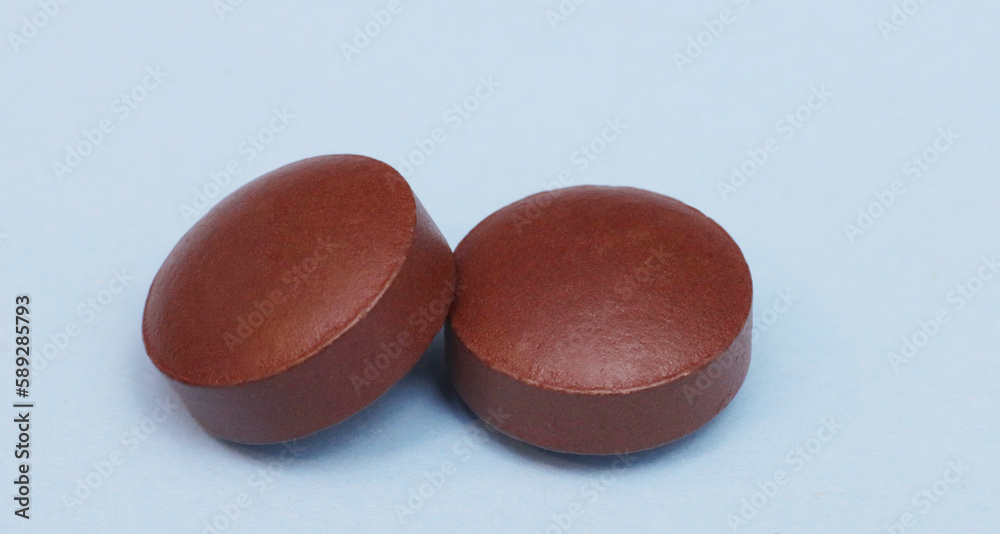 Close-up of two pills on a blue background. Close-up of two pills on a blue background.