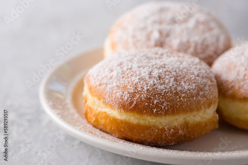 delicious donuts berliners with filling sprinkled with powdered sugar on a white plate