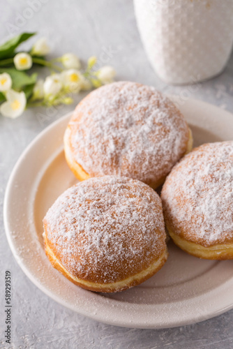 donuts berliners with filling sprinkled with powdered sugar on a white plate