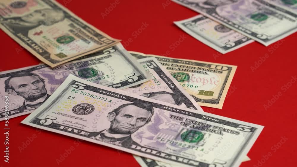 Money falling on table. Dropping lot of five ten twenty dollars paper banknotes on red background Money falling on table. Dropping lot of five ten twenty dollars paper banknotes on red background
