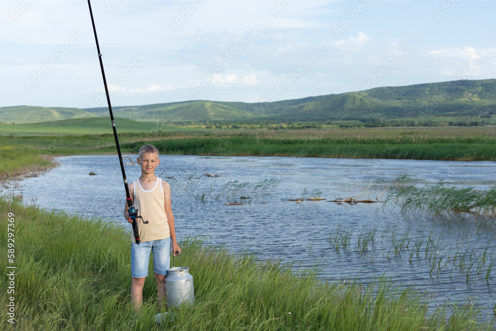 Little boy is fishing at sunset on the lake. Summer holidays in a village. Rest in nature, away from the city Little boy is fishing at sunset on the lake. Summer holidays in a village. Rest in nature, away from the city