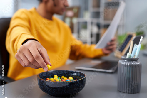 Foto Close up of young man eating snacks while working or studying at home, focus on
