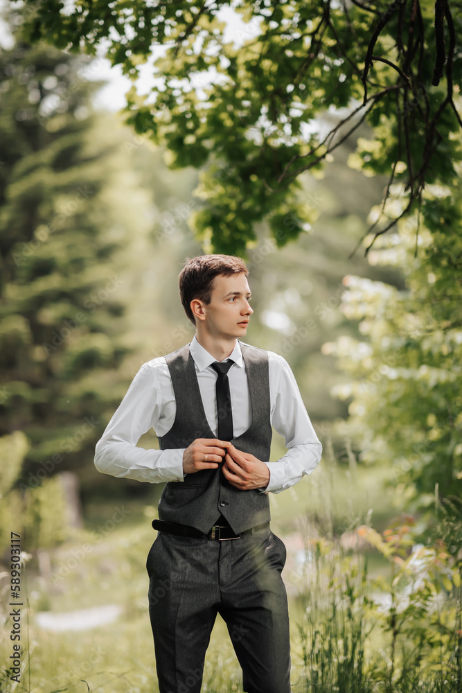 Happy stylish groom buttoning his jacket and looking away. Groom in a vest. Portrait of the groom. Spring wedding Happy stylish groom buttoning his jacket and looking away. Groom in a vest. Portrait of the groom. Spring wedding