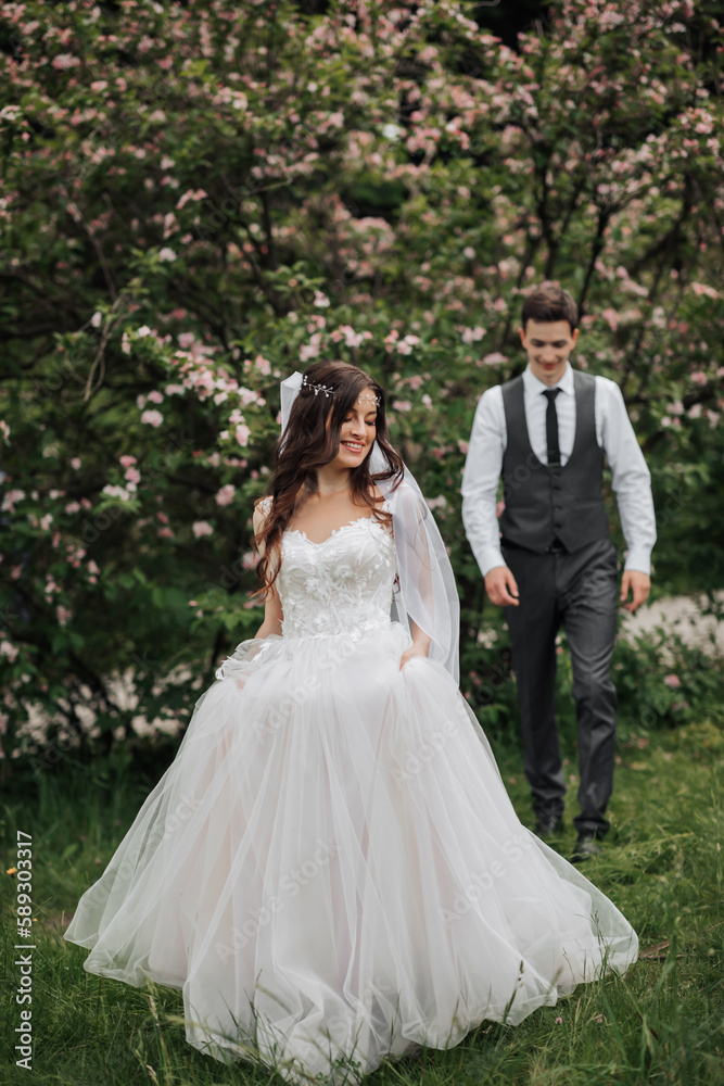 Happy stylish groom walking to the bride. The bride is in the foreground. Groom in a vest. Portrait of the groom. Spring wedding Happy stylish groom walking to the bride. The bride is in the foreground. Groom in a vest. Portrait of the groom. Spring wedding