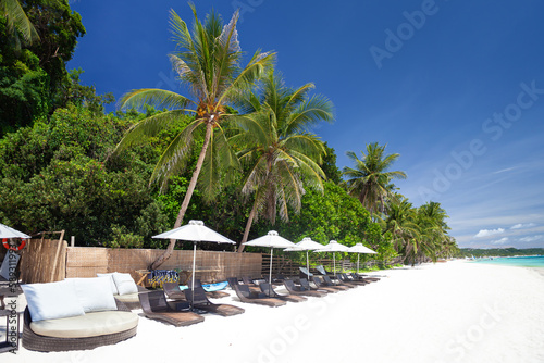 Fototapeta Naklejka Na Ścianę i Meble -  Sun umbrellas and beach chairs on tropical beach with palm trees