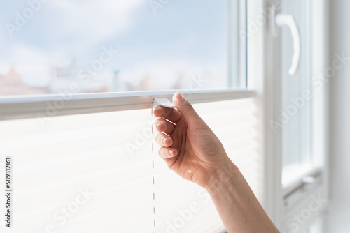 woman open cordless blind shutter on window