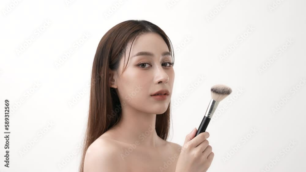 Beauty concept of 4k Resolution. Asian woman smiling with confidence in makeup with a brush on a white background. Beauty concept of 4k Resolution. Asian woman smiling with confidence in makeup with a brush on a white background.