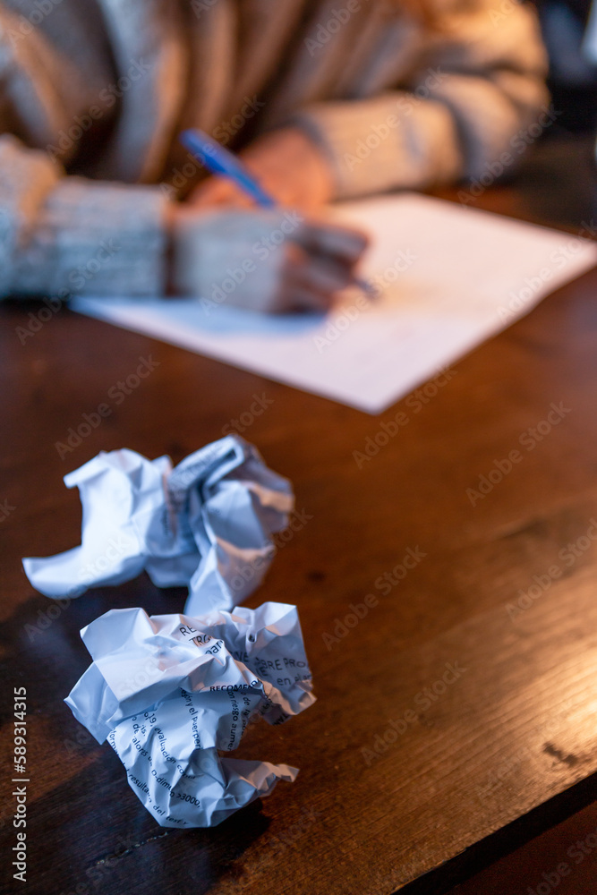Crumpled paper with a woman hand writing and studying on a wood table background