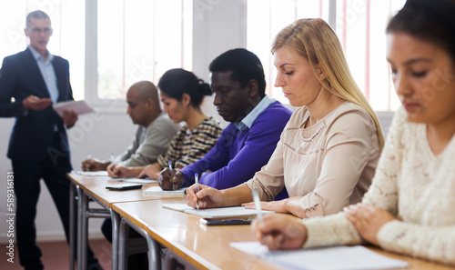 Portrait of focused female sitting at desk studying in classroom with colleagues